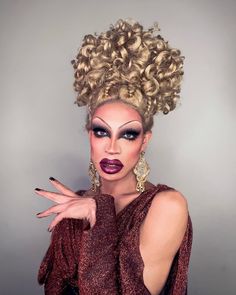 a woman with curly hair and makeup is posing for the camera while holding her hands out