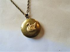 "A round brass locket with a swan on it is hanging from antiqued brass chain. The locket is a darkened brass and the swan is a made of raw brass giving it a golden color. You can select your length of chain at checkout. Locket measures approx. 1\" and opens to hold two small pictures. Necklace will come in a gift box and bow ready for gift giving. Enter back into store: rhondastreasures.etsy.com   RhondasTreasures" Ruby Locket, Swan Jewelry, Swan Necklace, Mia 3, Dope Jewelry, Small Pictures, Funky Jewelry, Jewelry Lookbook, Girly Jewelry