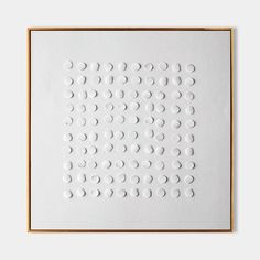 a white square with circles on it in front of a gold framed wall mounted art piece