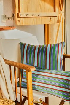 a wooden rocking chair sitting in front of a kitchen counter with a striped pillow on it