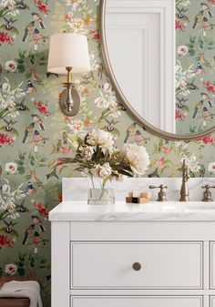 a bathroom with floral wallpaper and a round mirror