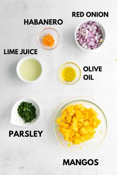 ingredients to make mango smoothie laid out on a white counter top, including lime juice, olive oil, parsley, mangos and red onion