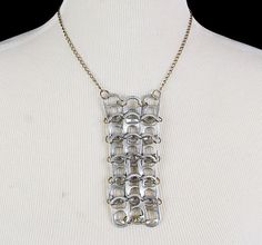 a white mannequin wearing a silver necklace with metal links on it's neck