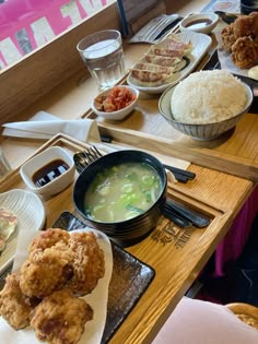 a wooden table topped with plates and bowls filled with different types of food on top of it