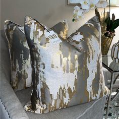 two gray and gold pillows sitting on top of a couch