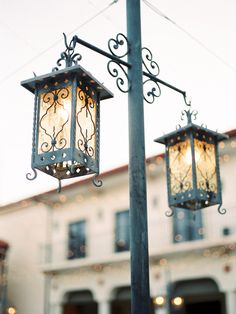 two street lamps on a pole in front of a building