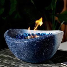 a blue bowl sitting on top of a table next to a cell phone and plant