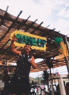 a man holding up a sign under a wooden structure