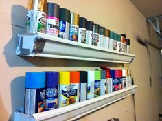 two white shelves filled with different types of spray paint