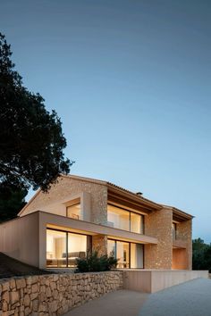 an exterior view of a modern house with stone walls and large windows at night time