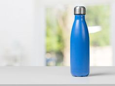 a blue water bottle sitting on top of a white counter next to an open window