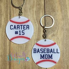 two baseball key chains with the number fifteen and one ball on them, sitting next to each other