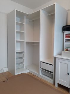 an empty white closet with shelves and drawers on the floor, next to a dresser