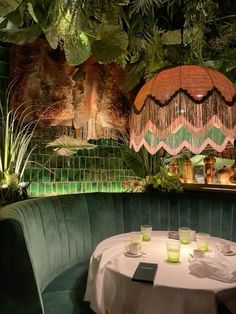 a green booth with white table cloths and greenery