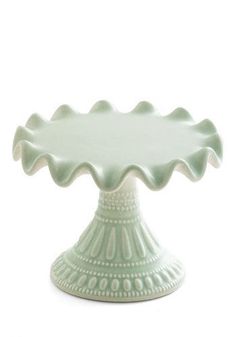 a green ceramic cake plate with scalloped designs on the rim and bottom, set against a white background