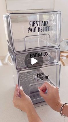 a person is holding a pen in front of three plastic containers that are labeled first aid, pain relief, and pandadiss