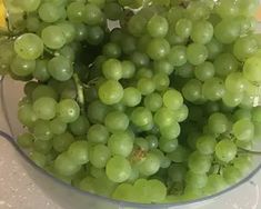 a glass bowl filled with green grapes on top of a counter