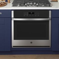 a kitchen with blue cabinets and white counter tops, stainless steel stove top and built - in oven