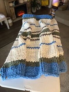 a crocheted blanket sitting on top of a white laptop computer case in a living room