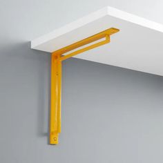 a close up of a yellow shelf on a wall with a white ceiling and gray walls