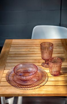 three glass cups and two plates on a wooden table