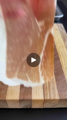 a person cutting up meat on top of a wooden cutting board