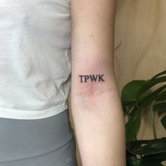 a woman with a small tpwk tattoo on her arm