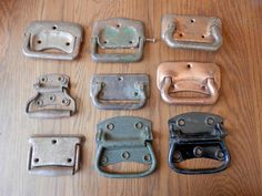 several different types of metal buckles on a wooden table with one missing the handle