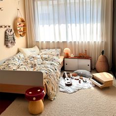 a bed room with a neatly made bed and various items on the floor next to it