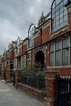 a row of red brick buildings next to a black iron fence and gated sidewalk