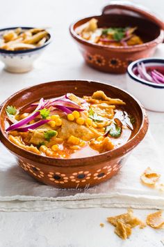 two bowls filled with different types of food on top of a white table next to other dishes