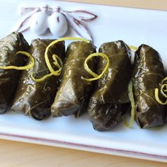 some stuffed grape leaves are on a white plate with yellow string wrapped around the edges