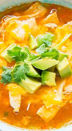 a bowl of soup with tortilla, avocado and cilantro