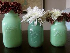 three mason jars with flowers in them sitting on a table