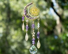 a sun and moon wind chime hanging from a tree with purple beaded beads