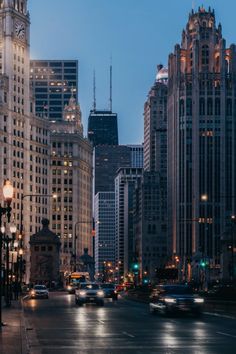 a city street filled with lots of tall buildings and traffic at night in the evening