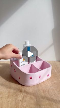 a person is holding a container with soap and lotion in it on a wooden table