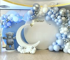 balloons are arranged around the moon and teddy bear in front of an arch decorated with stars