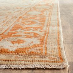 an orange and white rug with fringes on the floor in front of a wooden floor