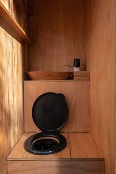 a toilet in a wooden room with no lid on the seat and shelf above it