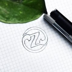 a pen sitting on top of a piece of paper next to a green leaf with the letter z in it