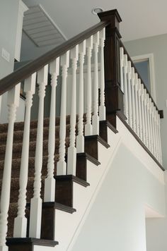 a staircase with white railings and brown carpet