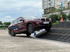 a red bmw suv parked on the side of a ramp in front of a building