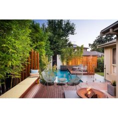 an outdoor deck with chairs and table next to a swimming pool surrounded by greenery