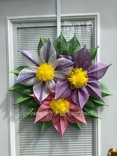 two paper flowers sitting on top of each other in front of a white window sill