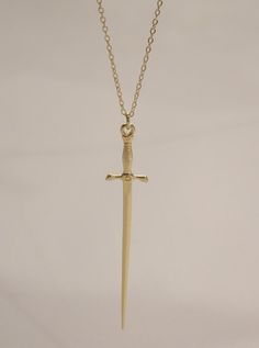 The Silvet Long Dagger Necklace is a must have! This sleek long dagger sword necklace was designed for both men and women and features a lux sword pendant suspended on a diamond cut chain. Bolden your look and pair with these cool pieces! - The Dagger Earrings (available in gold and silver) - The Thin Herringbone Chain Necklace - The Scorpion Necklace Available in 24K gold or rhodium plating over steel Patent plating & sealant technology to ensure durability and long lasting wear Made in Los Ang Gold Dagger Necklace, Granola Goth, Eric Aesthetic, Scorpion Necklace, Ruby Heart Necklace, Knife Necklace, Dagger Necklace, Dagger Earrings, Herringbone Chain