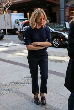 a woman is walking down the street with her arms crossed