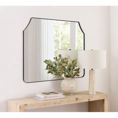 a mirror sitting on top of a wooden table next to a lamp