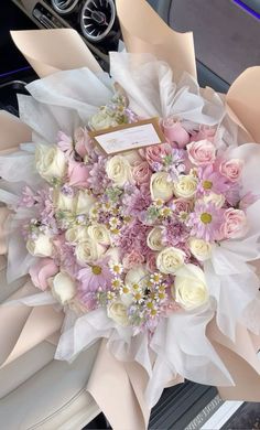 a bouquet of flowers sitting on top of a car seat in front of a steering wheel