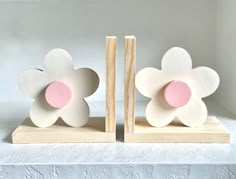 two wooden bookends with pink and white flowers on them, one holding a piece of wood